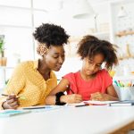 mother teaching daughter and helping her with homework at home