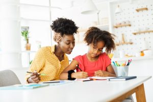 mother teaching daughter and helping her with homework at home