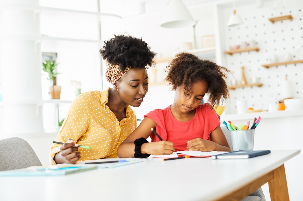 mother teaching daughter and helping her with homework at home
