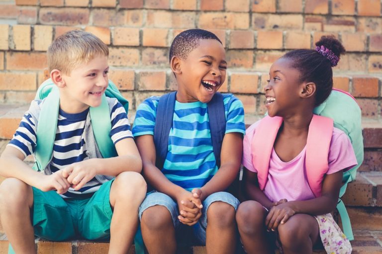 Happy mixed race school kids sitting together on staircase